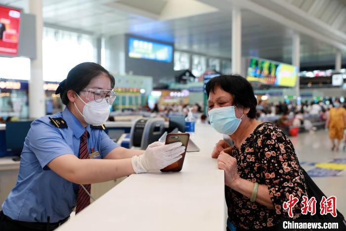 南宁东站工作人员帮助老年旅客查看购票信息