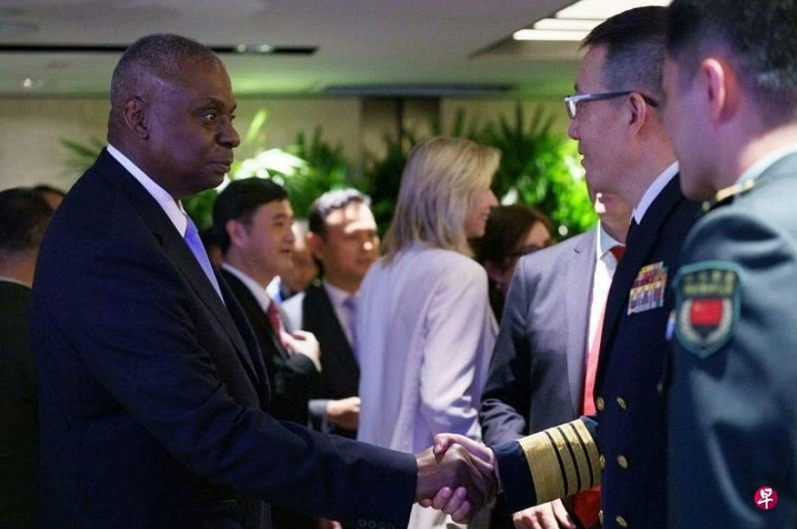 美国防长奥斯汀（左）星期六（6月1日）在香格里拉对话场边举行的防长圆桌讨论活动上与中国防长董军握手 ...
